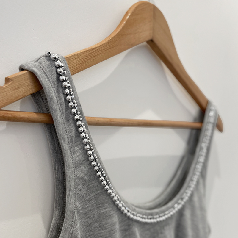 Confeccionada en tejido de algodón, esta musculosa destaca por su elegancia. Su diseño realizado con canutillos y perlas bordada a mano sobre el cuello le agrega un toque de elegancia que te hará destacar en cualquier ocasión.